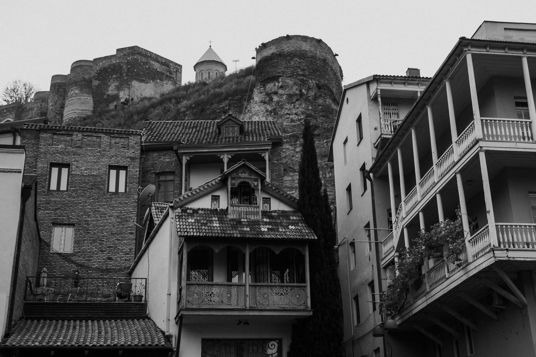Black and white photo capturing Tbilisi's historic architecture with fortress backdrop.