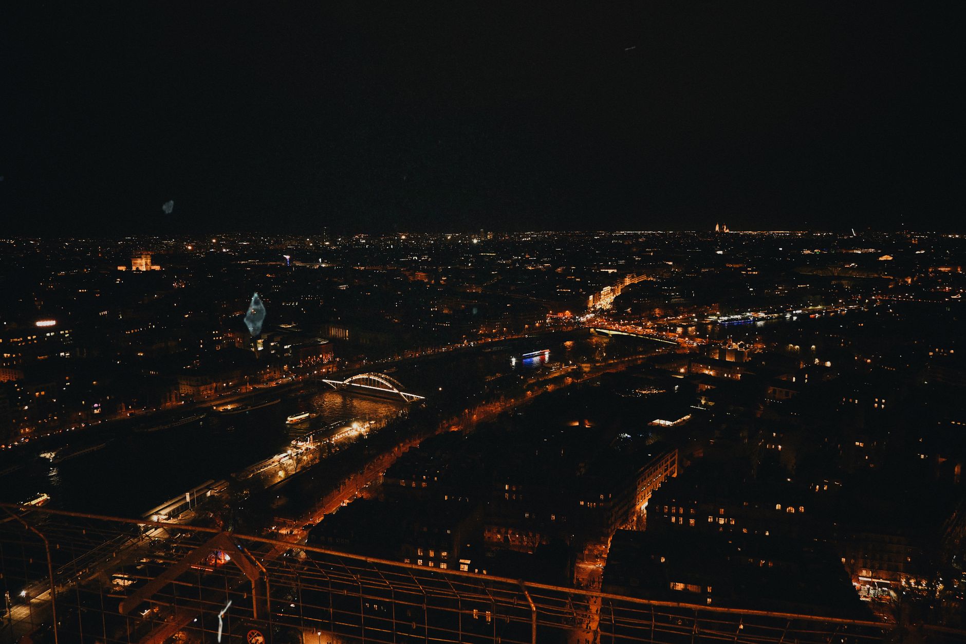 Stunning night view of Paris cityscape from Eiffel Tower with illuminated bridges and streets.