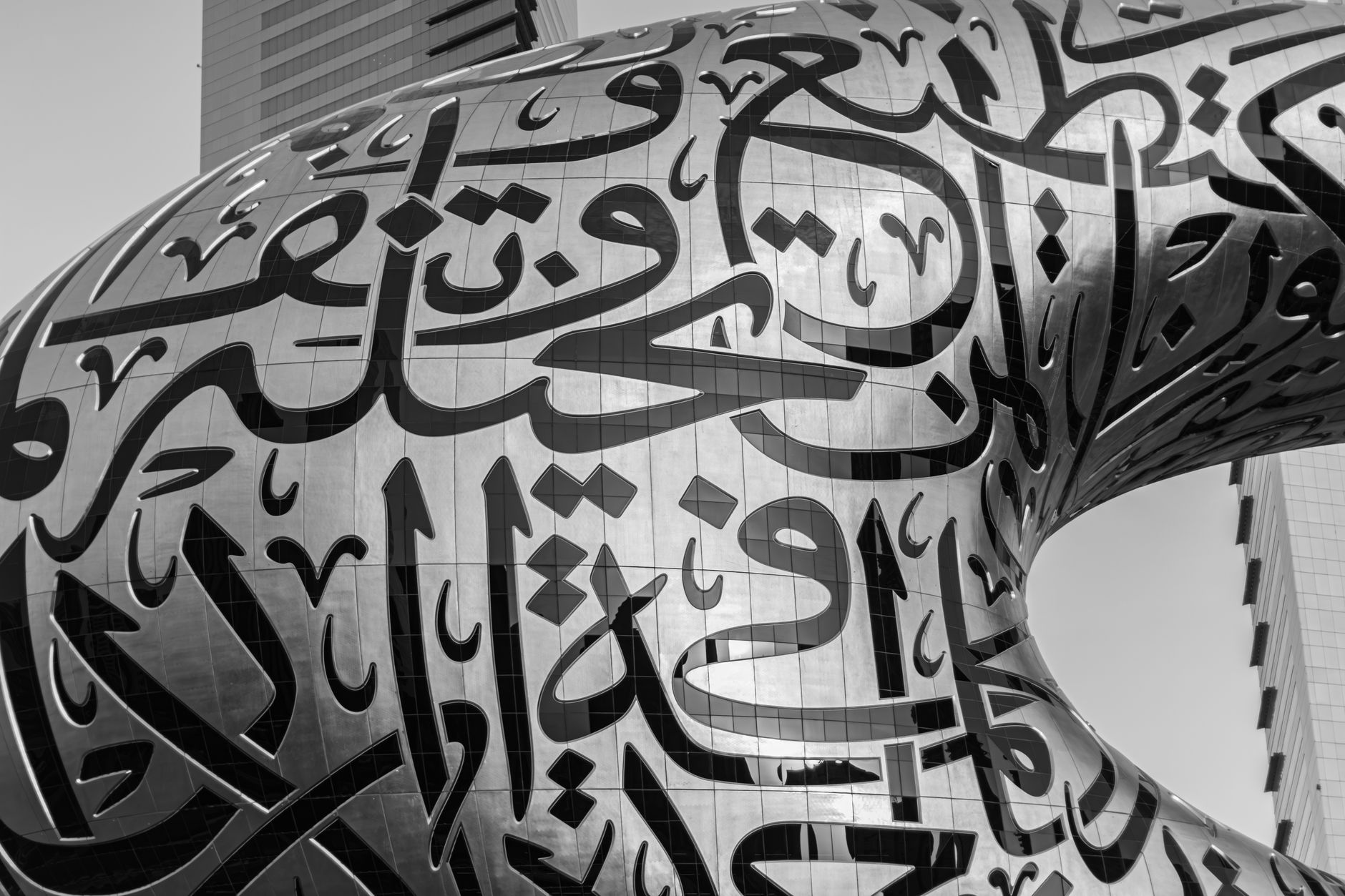 A dramatic black and white close-up of Arabic calligraphy on the Museum of the Future, Dubai, showcasing modern architecture.